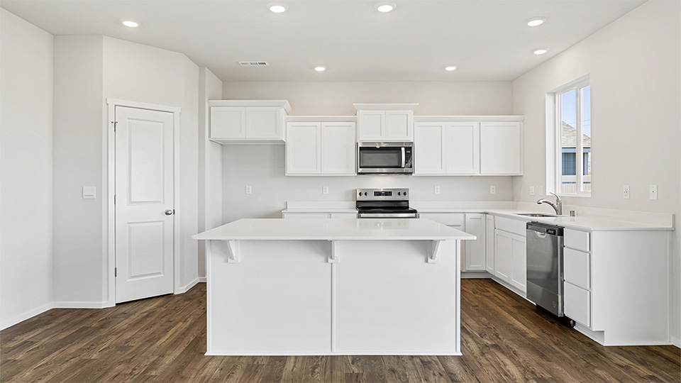 Kitchen with shaker cabinets, quartz counters, stainless steel appliances, pantry, and an island with a breakfast bar