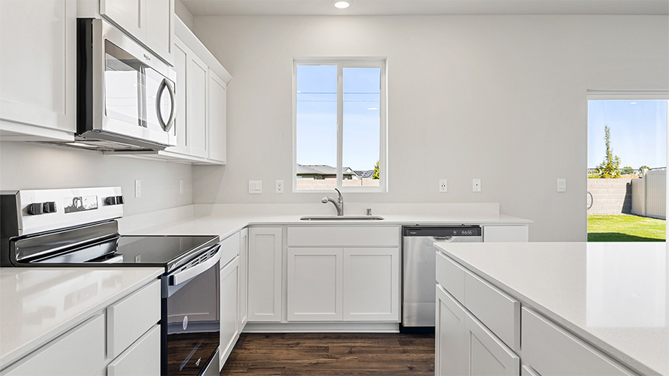Kitchen with shaker cabinets, quartz counters, stainless steel appliances, pantry, and an island with a breakfast bar
