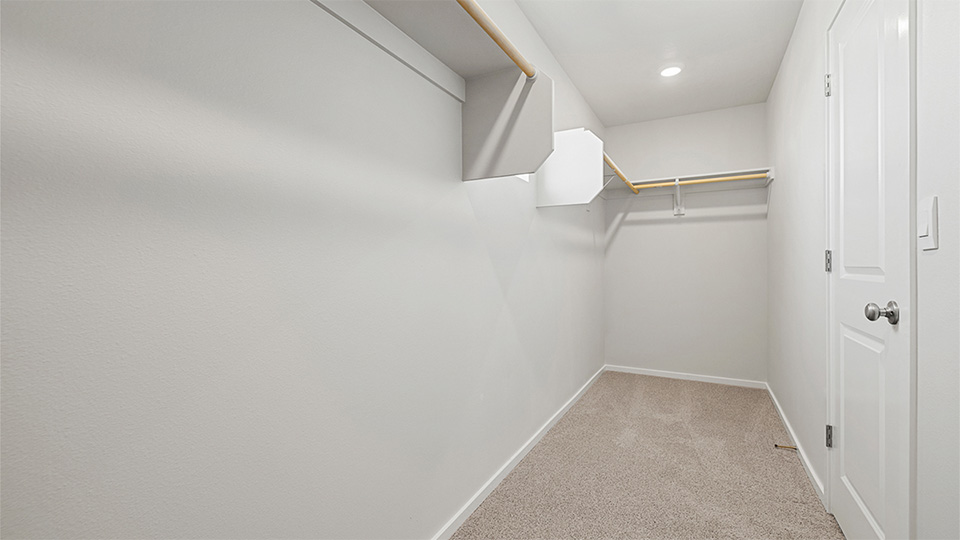 Primary bedroom walk-in closet with built-in shelves