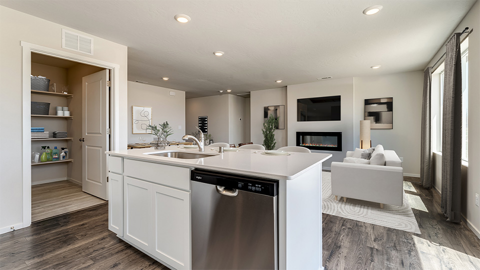 Kitchen with shaker cabinets, quartz counters, stainless steel appliances, pantry, and an island with a breakfast bar