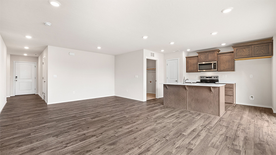 Kitchen with shaker cabinets, quartz counters, stainless steel appliances, pantry, and an island with a breakfast bar