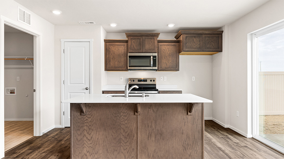 Kitchen with shaker cabinets, quartz counters, stainless steel appliances, pantry, and an island with a breakfast bar