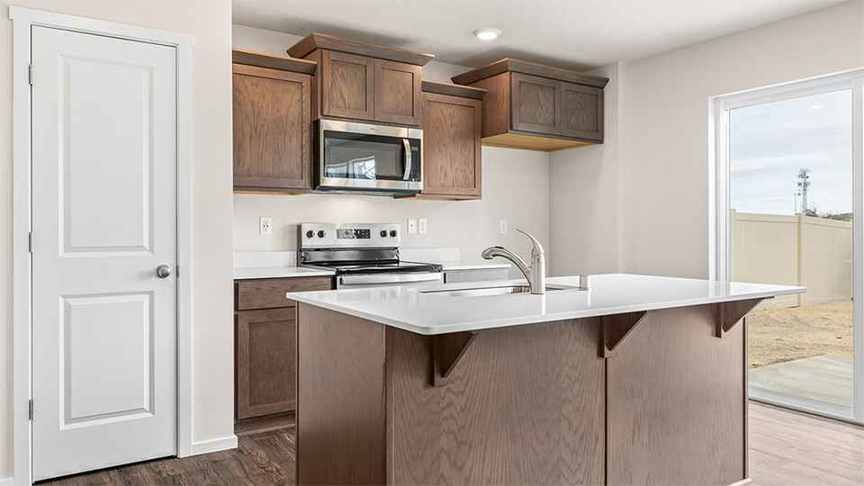 Kitchen with shaker cabinets, quartz counters, stainless steel appliances, pantry, and an island with a breakfast bar