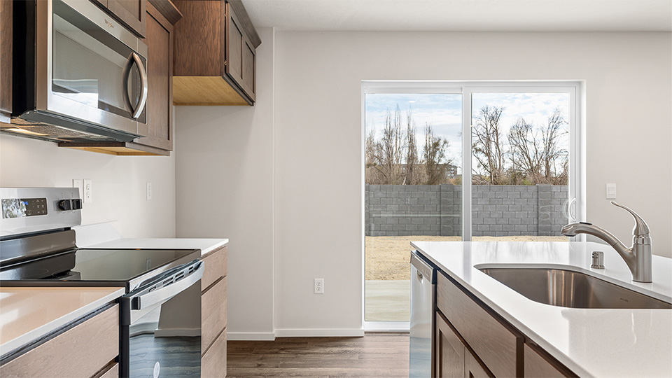 Kitchen with shaker cabinets, quartz counters, stainless steel appliances, pantry, and an island with a breakfast bar