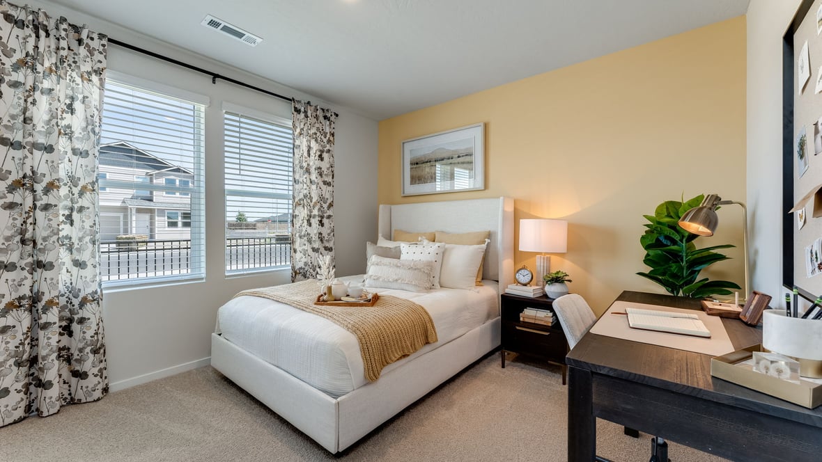 A guest bedroom with wall-to-wall carpet, window and a full-sized bed