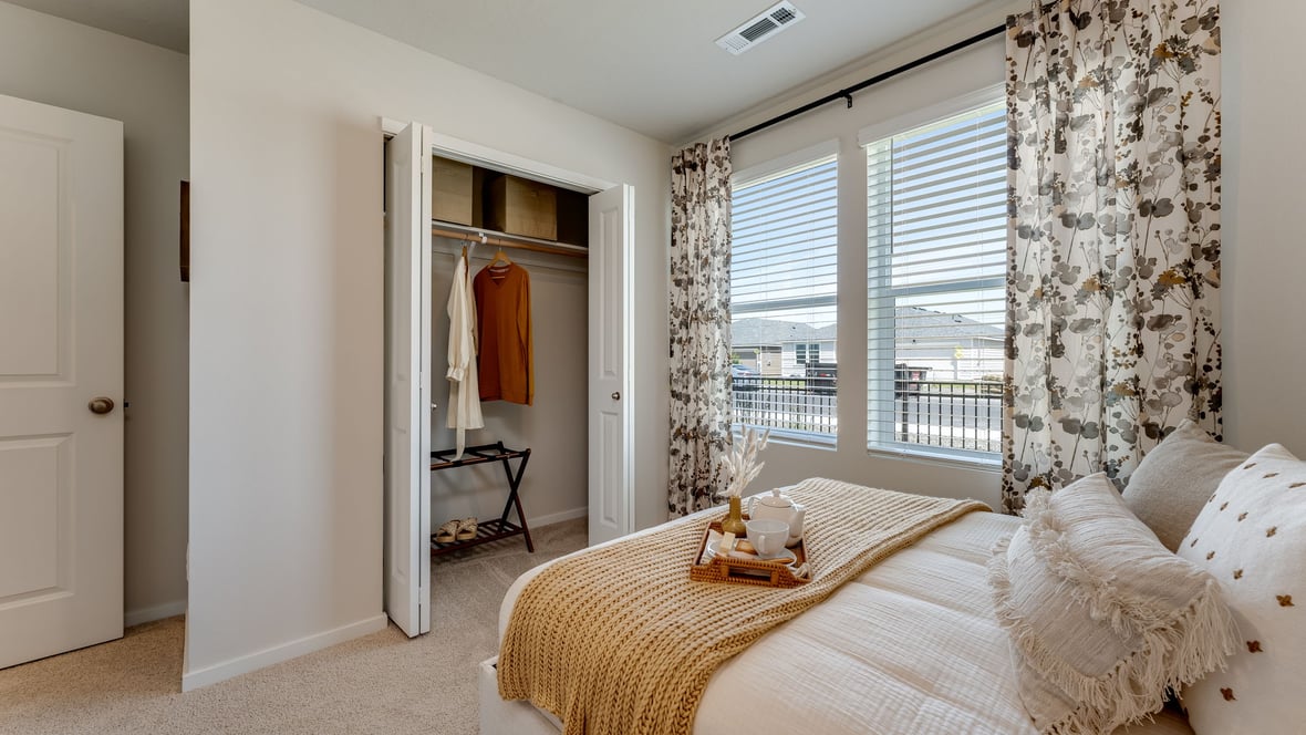 A guest bedroom with wall-to-wall carpet, window and a full-sized bed