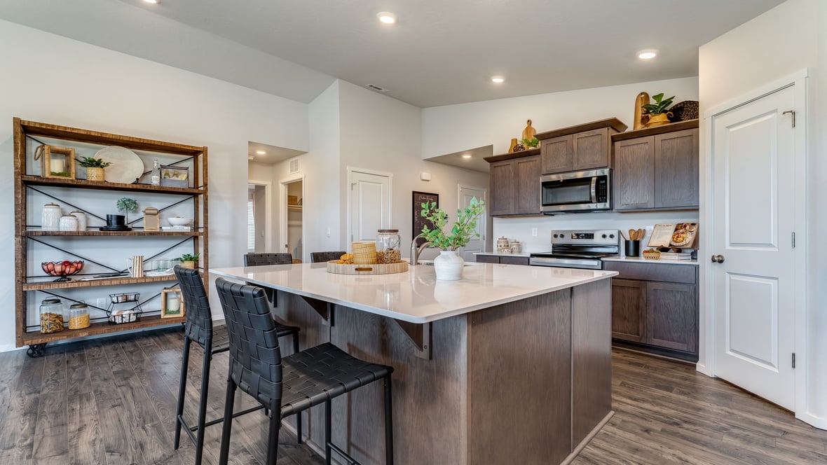 Kitchen with shaker cabinets, quartz counters, stainless steel appliances, pantry, and an island with a breakfast bar