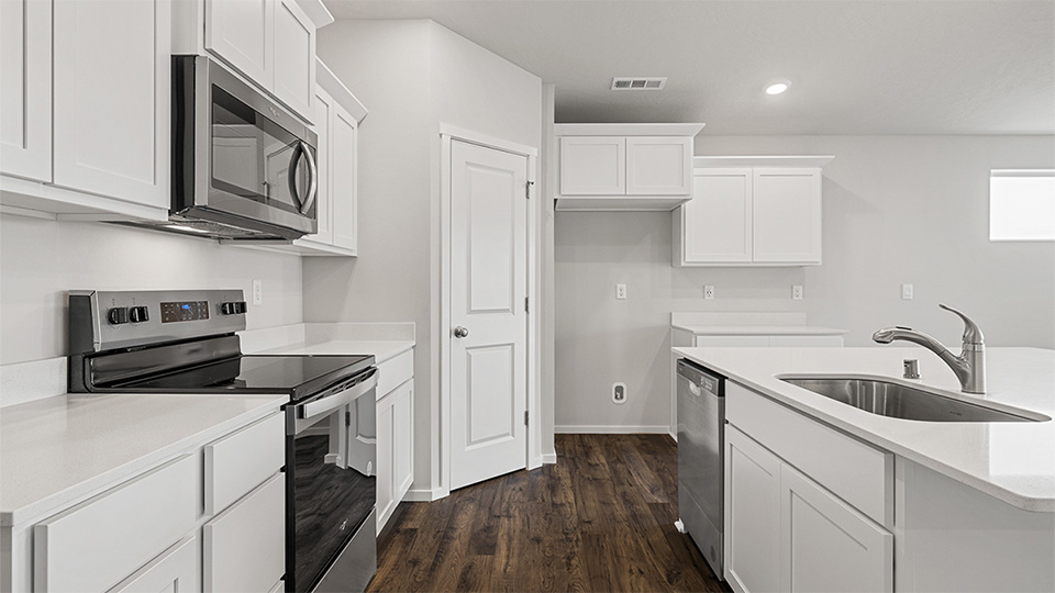 Kitchen with shaker cabinets, quartz counters, stainless steel appliances, pantry, and an island with a breakfast bar