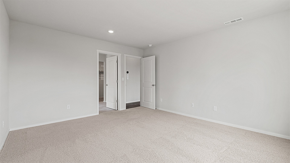 Primary bedroom with wall-to-wall carpet, a walk-in closet and an attached bathroom