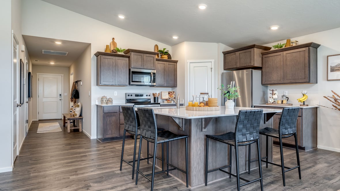 Kitchen with shaker cabinets, quartz counters, stainless steel appliances, pantry, and an island with a breakfast bar