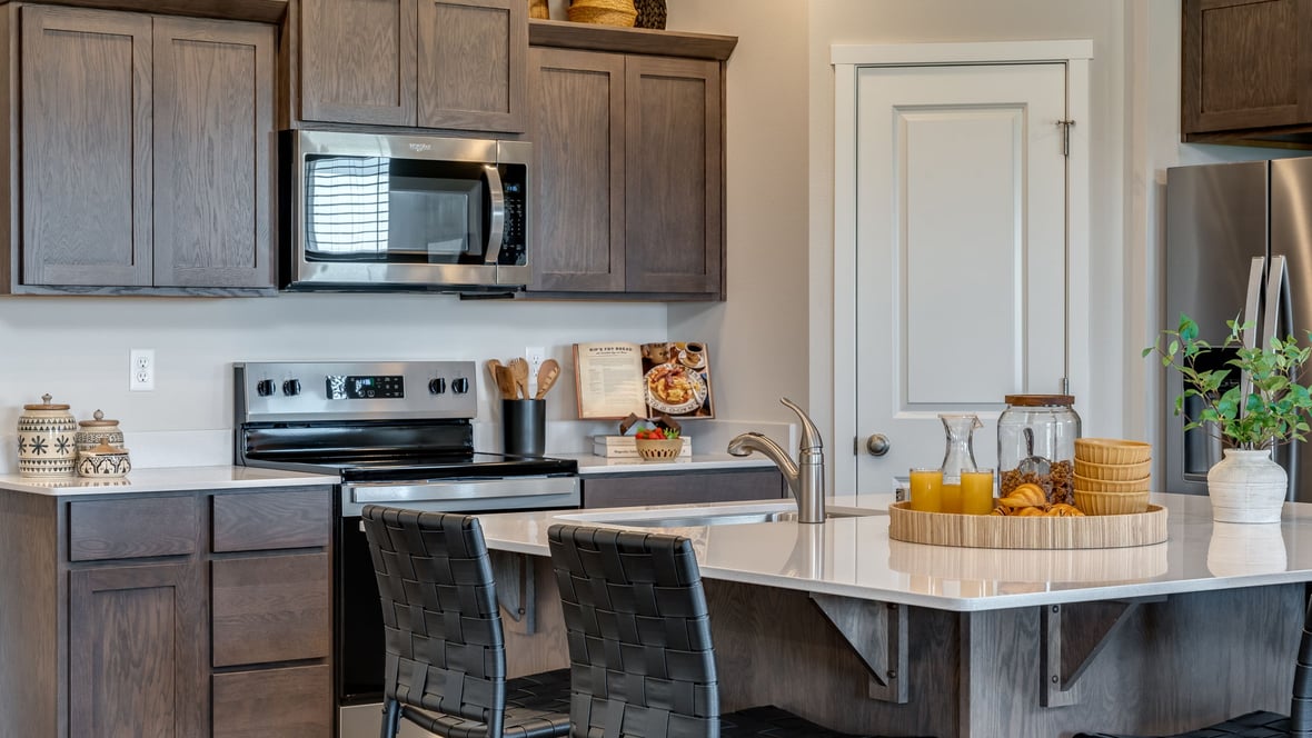 Kitchen with shaker cabinets, quartz counters, stainless steel appliances, pantry, and an island with a breakfast bar