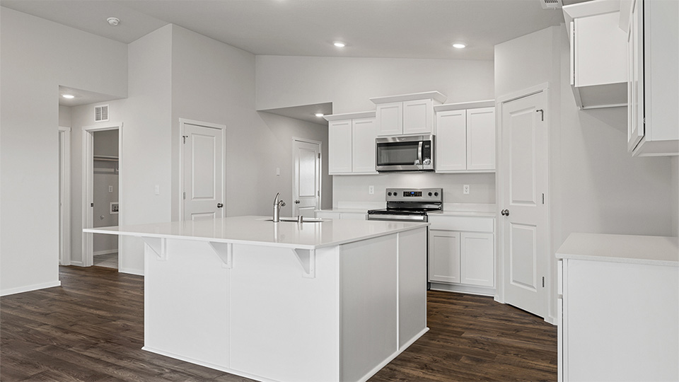 Kitchen with shaker cabinets, quartz counters, stainless steel appliances, pantry, and an island with a breakfast bar