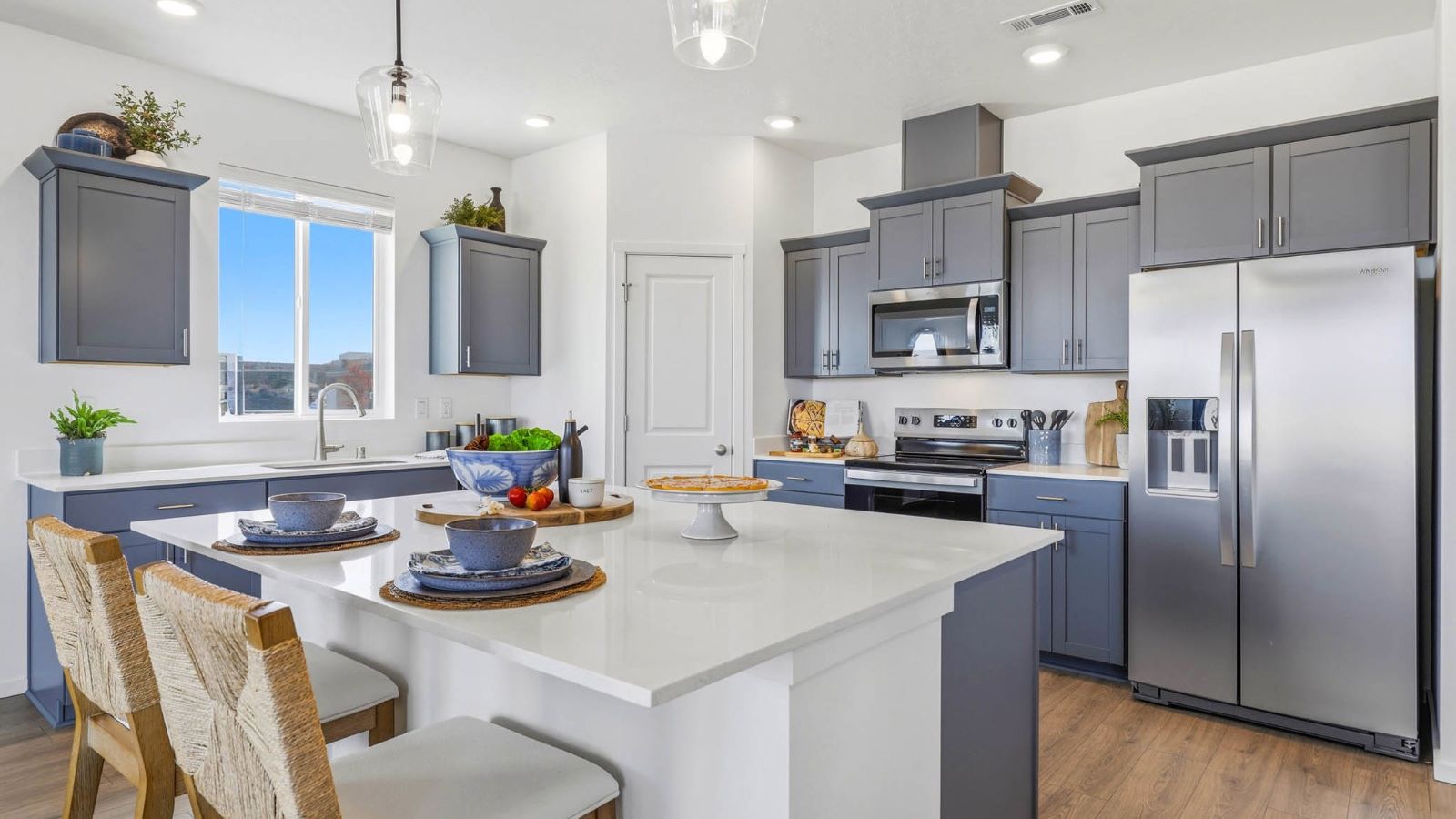 Kitchen with shaker cabinets, quartz counters, stainless steel appliances, pantry, and an island with a breakfast bar