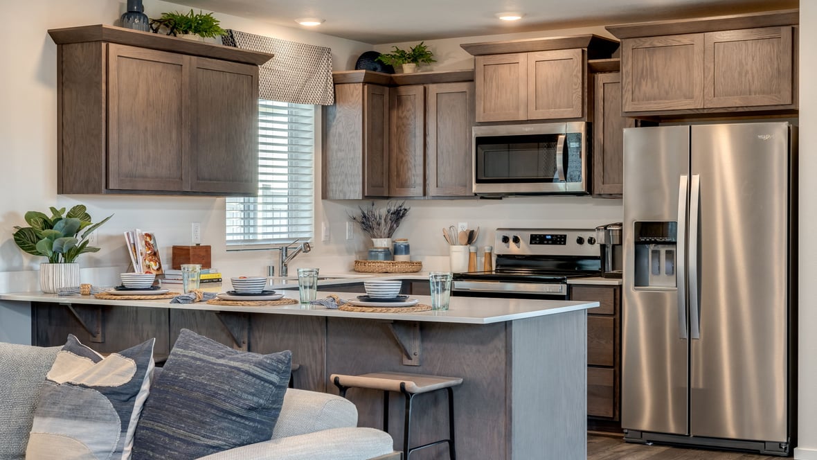 U-shaped kitchen with shaker cabinets, quartz counters, stainless steel appliances, pantry, and a breakfast bar