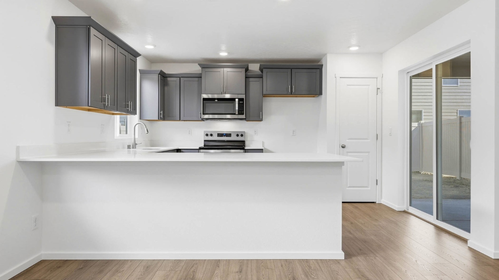 U-shaped kitchen with shaker cabinets, quartz counters, stainless steel appliances, pantry, and a breakfast bar