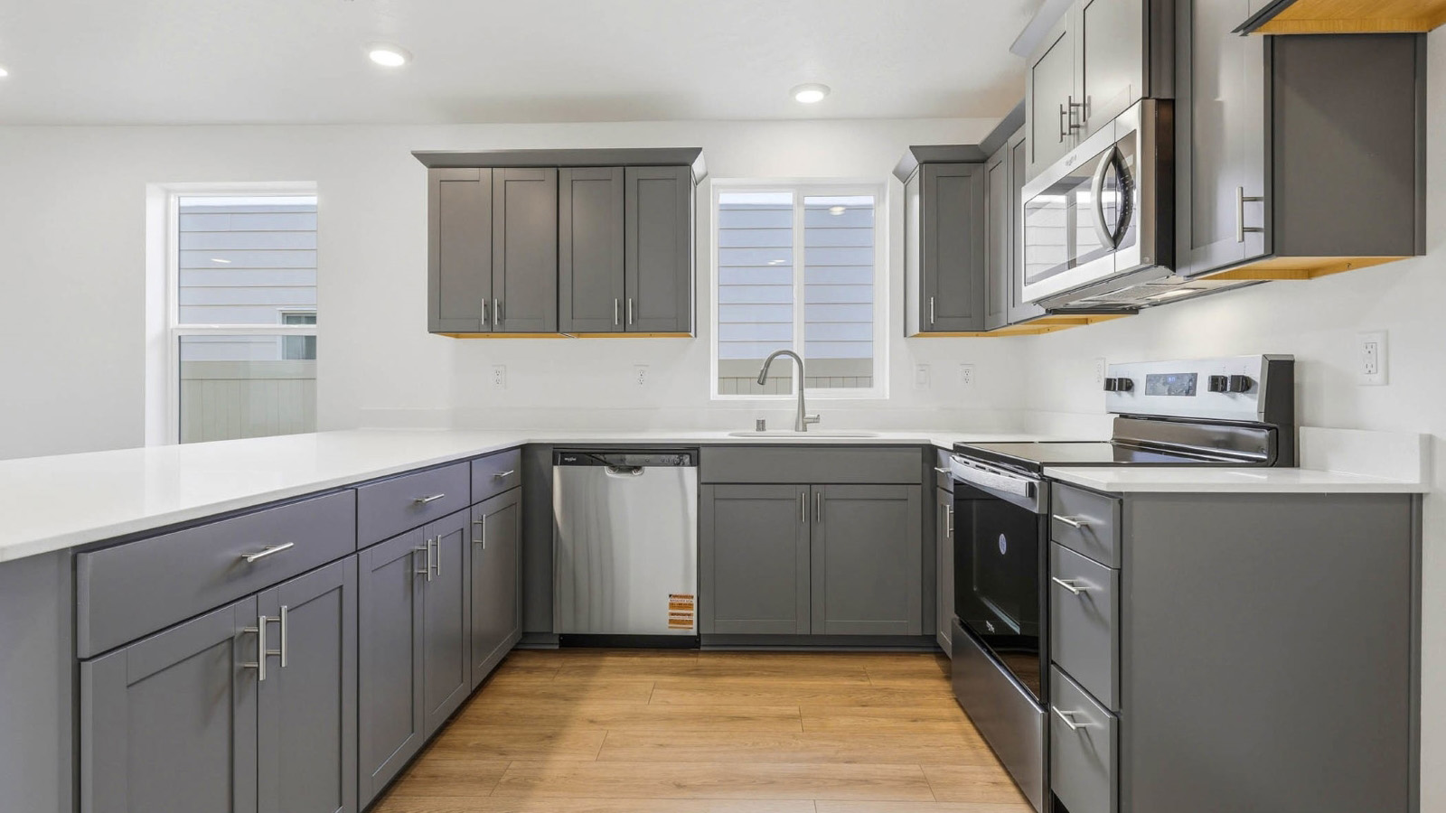 U-shaped kitchen with shaker cabinets, quartz counters, stainless steel appliances, pantry, and a breakfast bar