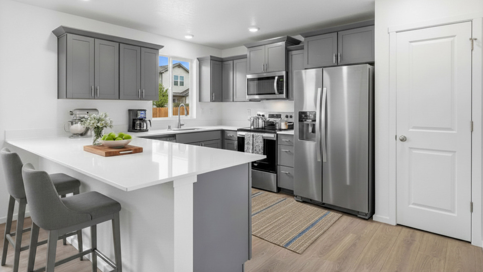 U-shaped kitchen with shaker cabinets, quartz counters, stainless steel appliances, pantry, and a breakfast bar