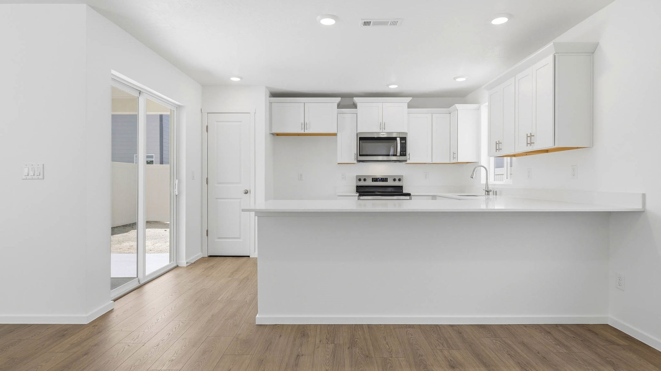 U-shaped kitchen with shaker cabinets, quartz counters, stainless steel appliances, pantry, and a breakfast bar