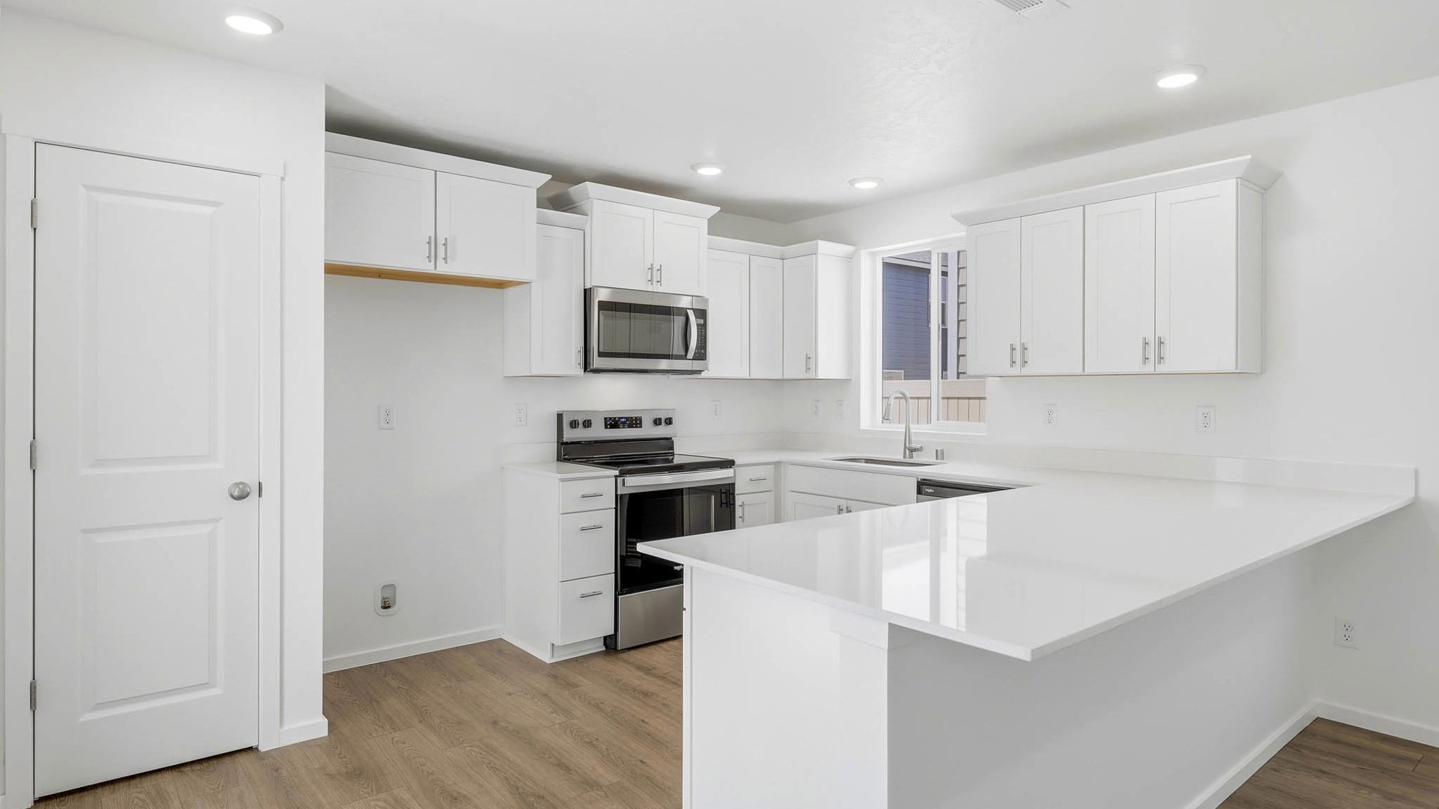 U-shaped kitchen with shaker cabinets, quartz counters, stainless steel appliances, pantry, and a breakfast bar
