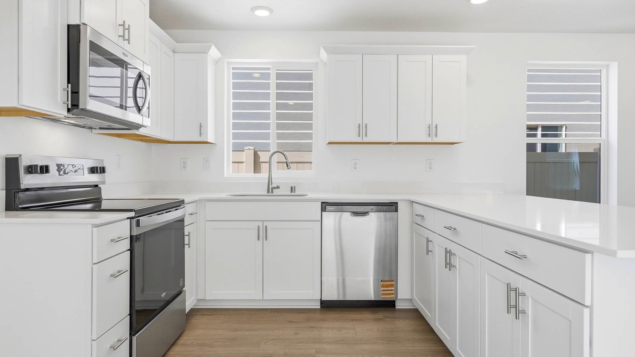 U-shaped kitchen with shaker cabinets, quartz counters, stainless steel appliances, pantry, and a breakfast bar