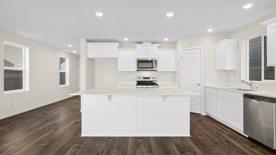 Kitchen with shaker cabinets, quartz counters, stainless steel appliances, pantry, and an island with a breakfast bar