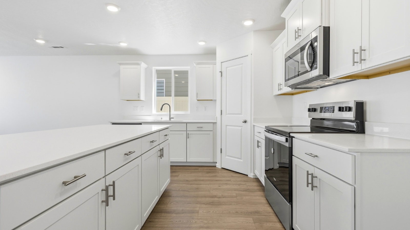 Kitchen with shaker cabinets, quartz counters, stainless steel appliances, pantry, and an island with a breakfast bar
