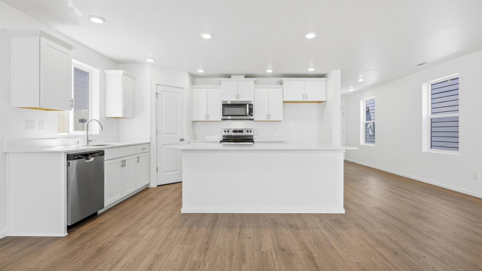 Kitchen with shaker cabinets, quartz counters, stainless steel appliances, pantry, and an island with a breakfast bar