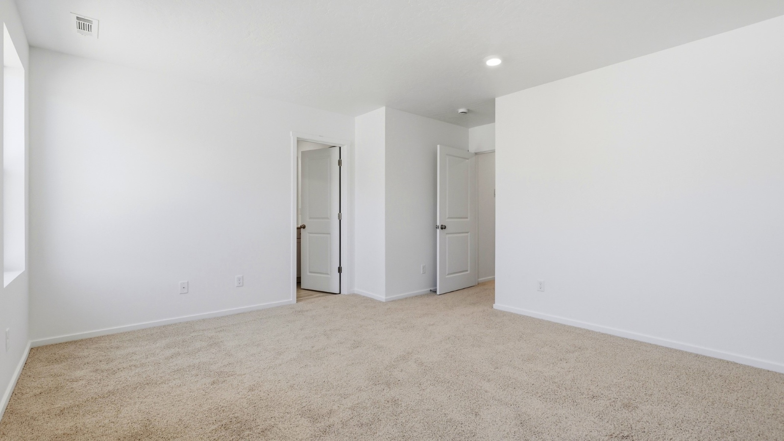 Primary bedroom with wall-to-wall carpet, a walk-in closet and an attached bathroom