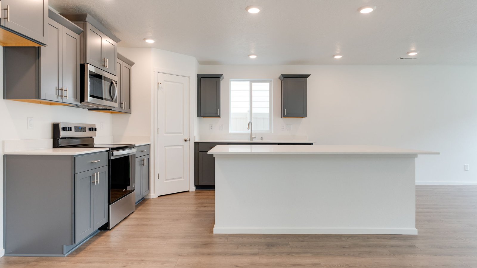 Kitchen with shaker cabinets, quartz counters, stainless steel appliances, pantry, and an island with a breakfast bar