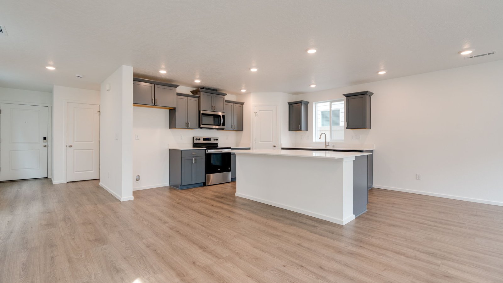 Kitchen with shaker cabinets, quartz counters, stainless steel appliances, pantry, and an island with a breakfast bar