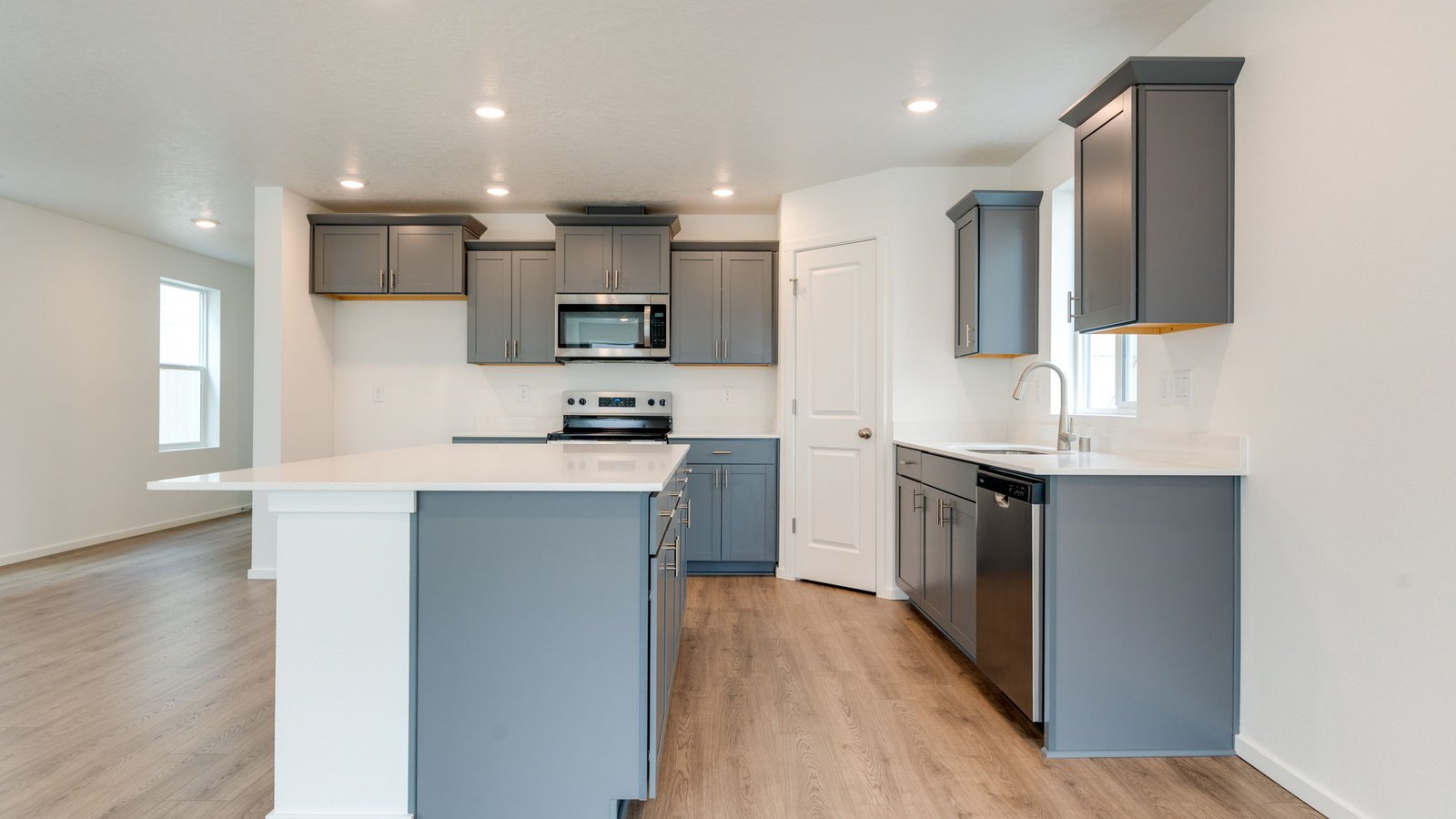 Kitchen with shaker cabinets, quartz counters, stainless steel appliances, pantry, and an island with a breakfast bar