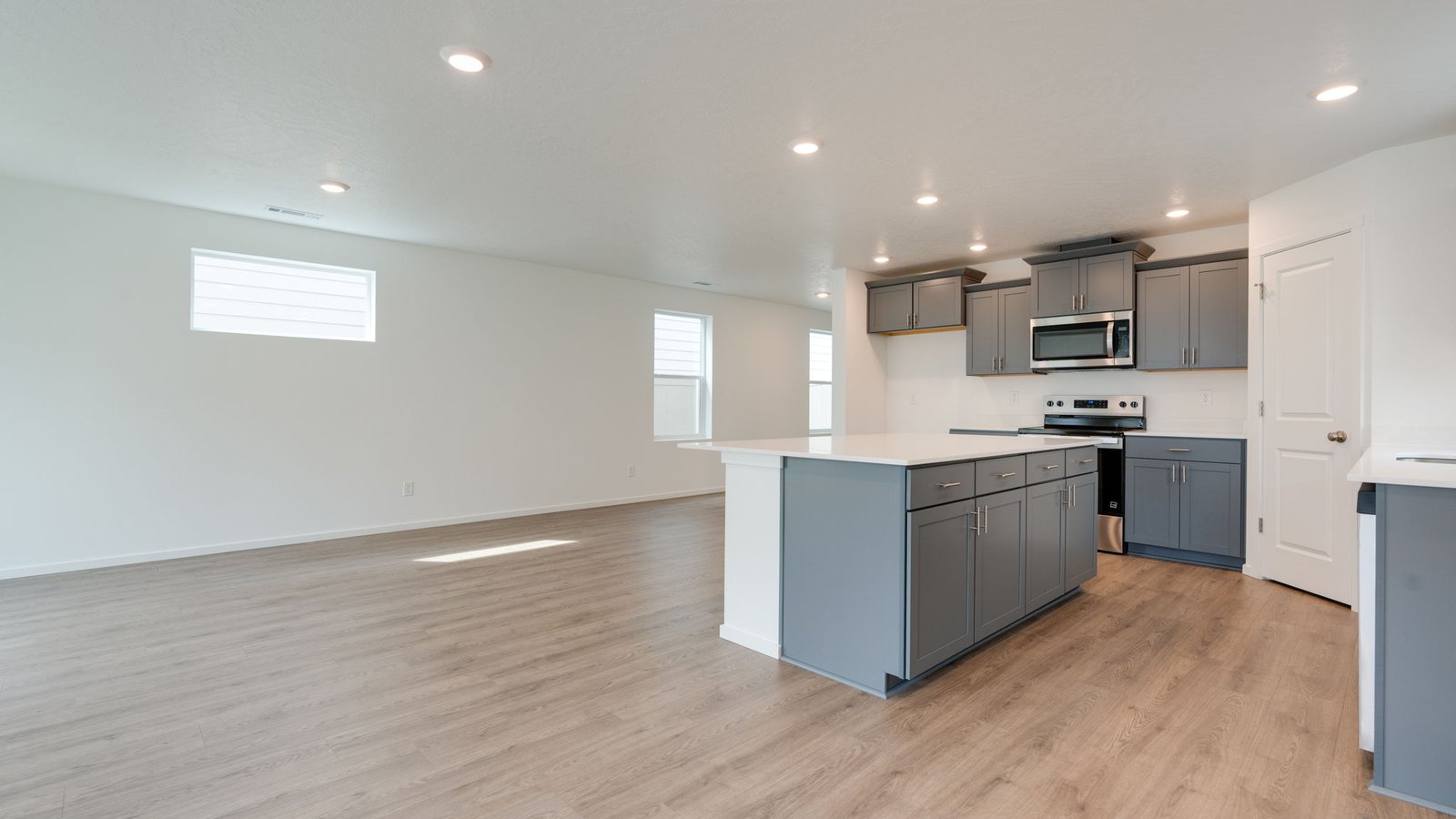 Kitchen with shaker cabinets, quartz counters, stainless steel appliances, pantry, and an island with a breakfast bar