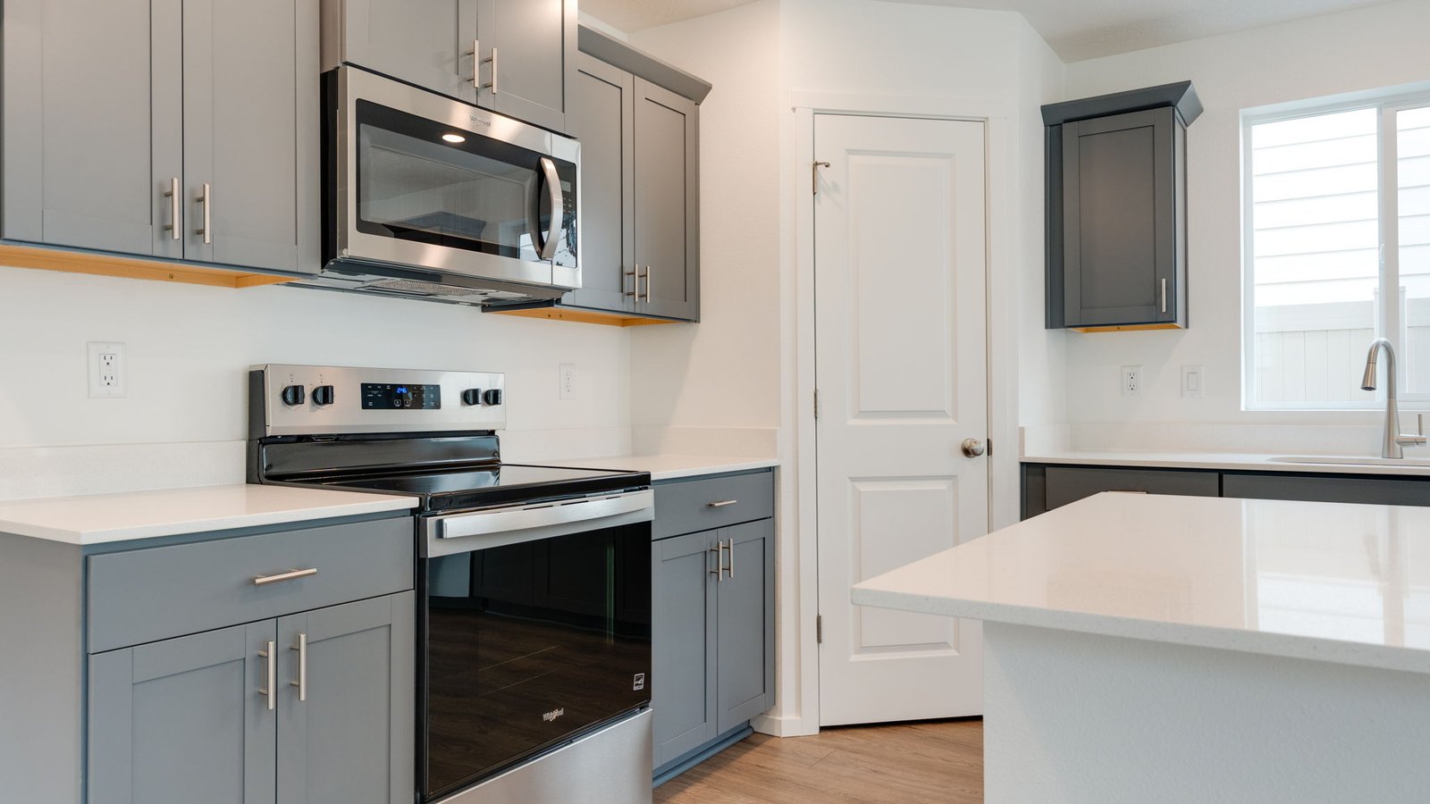 Kitchen with shaker cabinets, quartz counters, stainless steel appliances, pantry, and an island with a breakfast bar