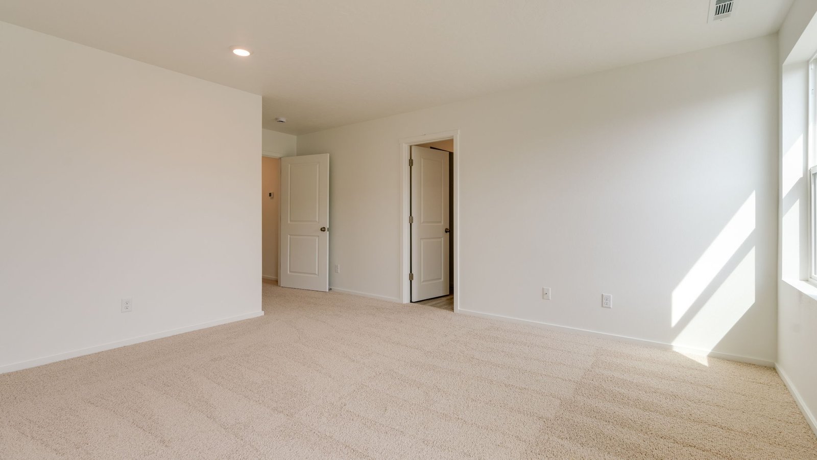Primary bedroom with wall-to-wall carpet, a walk-in closet and an attached bathroom