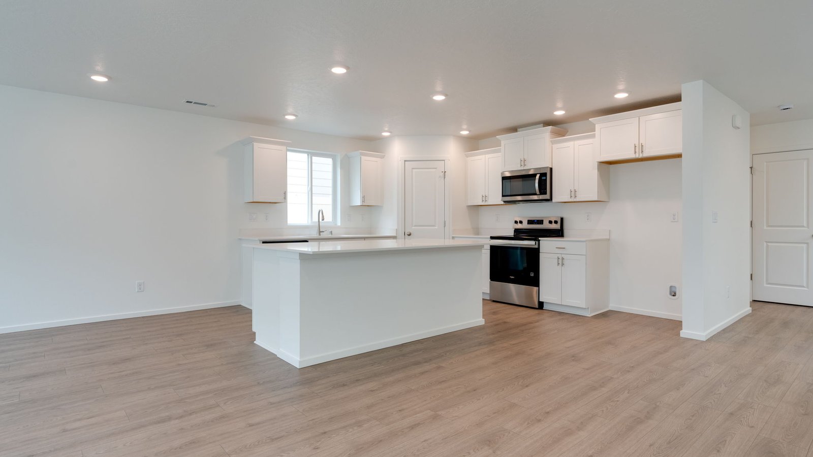 Kitchen with shaker cabinets, quartz counters, stainless steel appliances, pantry, and an island with a breakfast bar