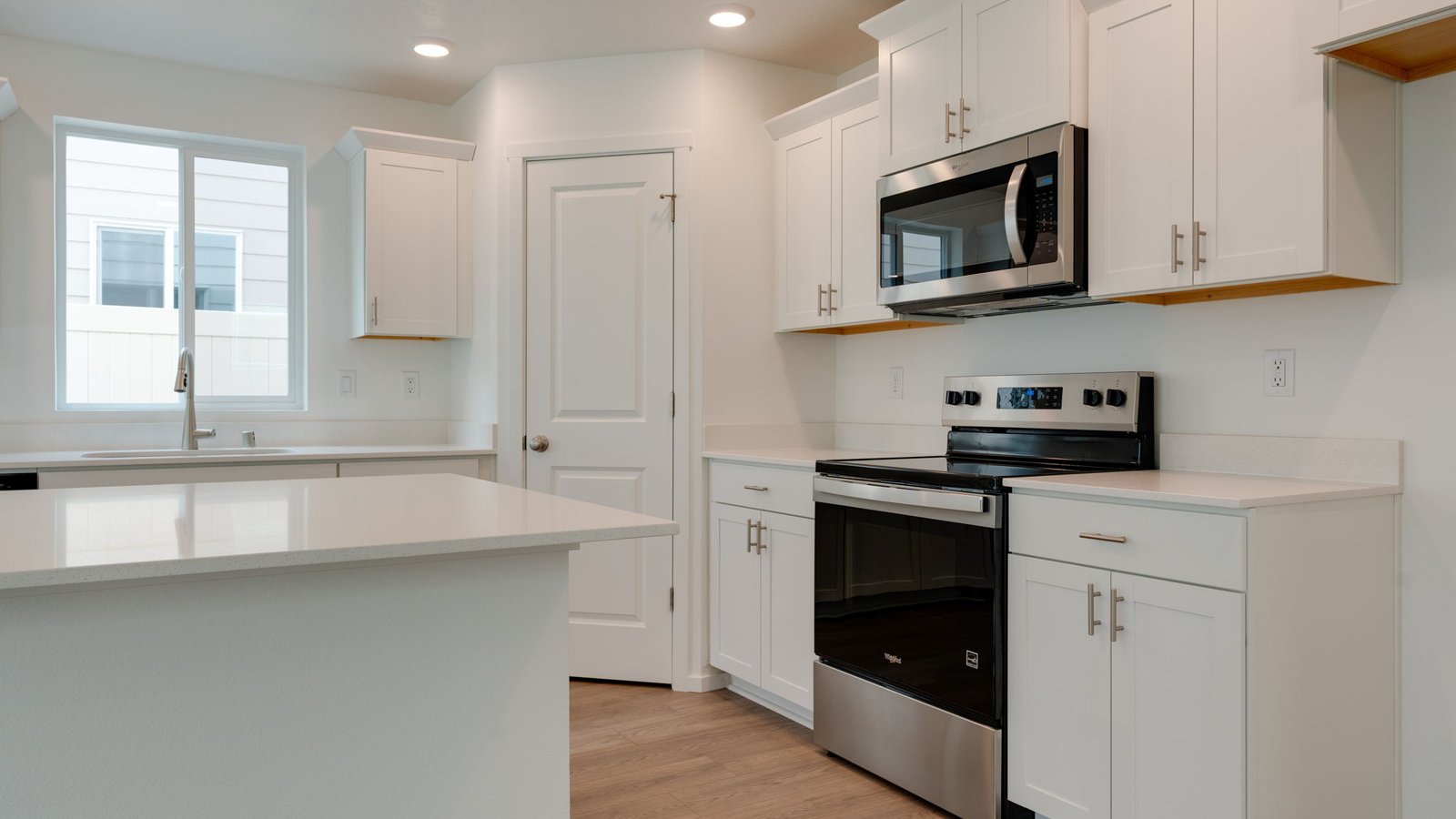 Kitchen with shaker cabinets, quartz counters, stainless steel appliances, pantry, and an island with a breakfast bar