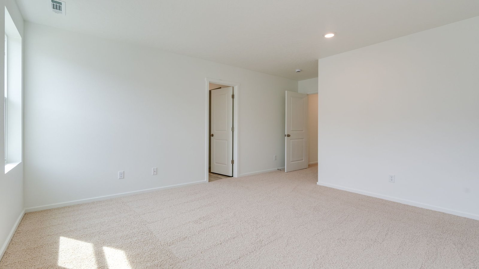 Primary bedroom with wall-to-wall carpet, a walk-in closet and an attached bathroom
