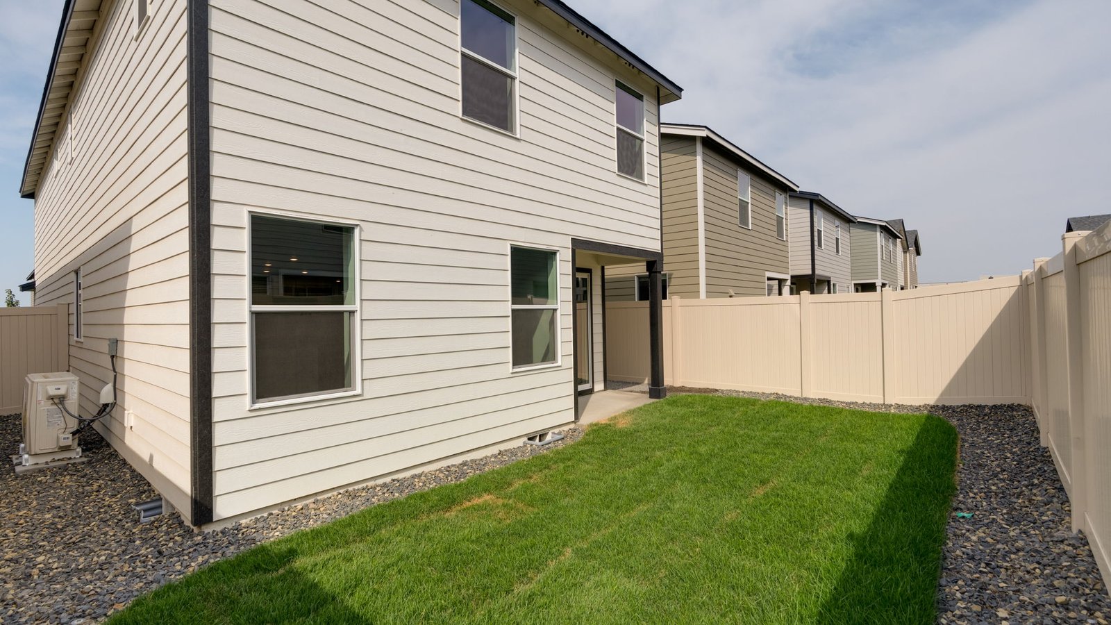 fully fenced backyard with sod lawn and a patio