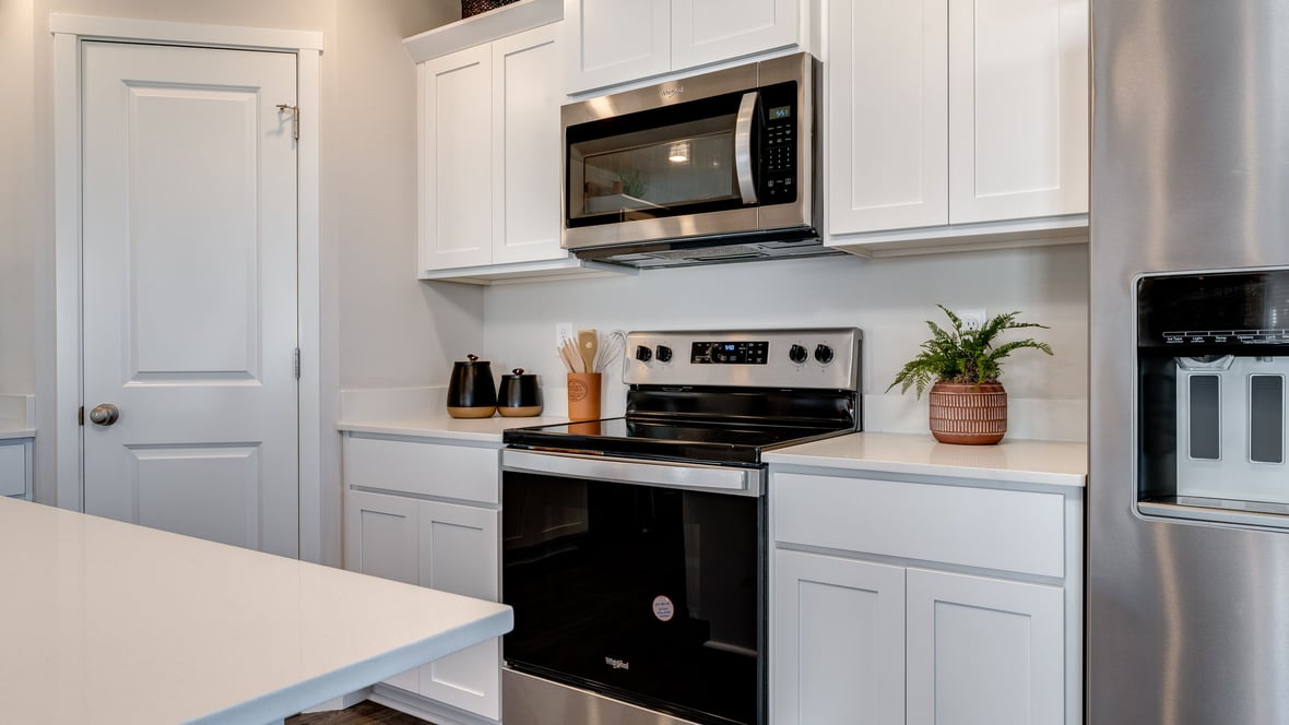Kitchen with shaker cabinets, quartz counters, stainless steel appliances, pantry, and an island with a breakfast bar
