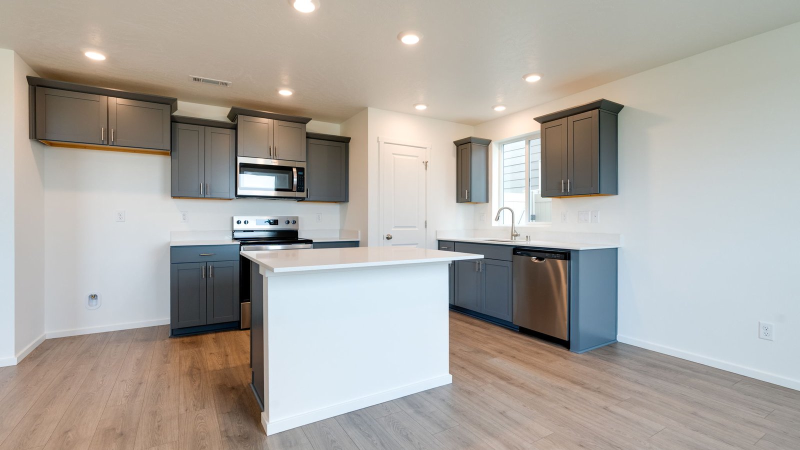 Kitchen with shaker cabinets, quartz counters, stainless steel appliances, pantry, and an island with a breakfast bar