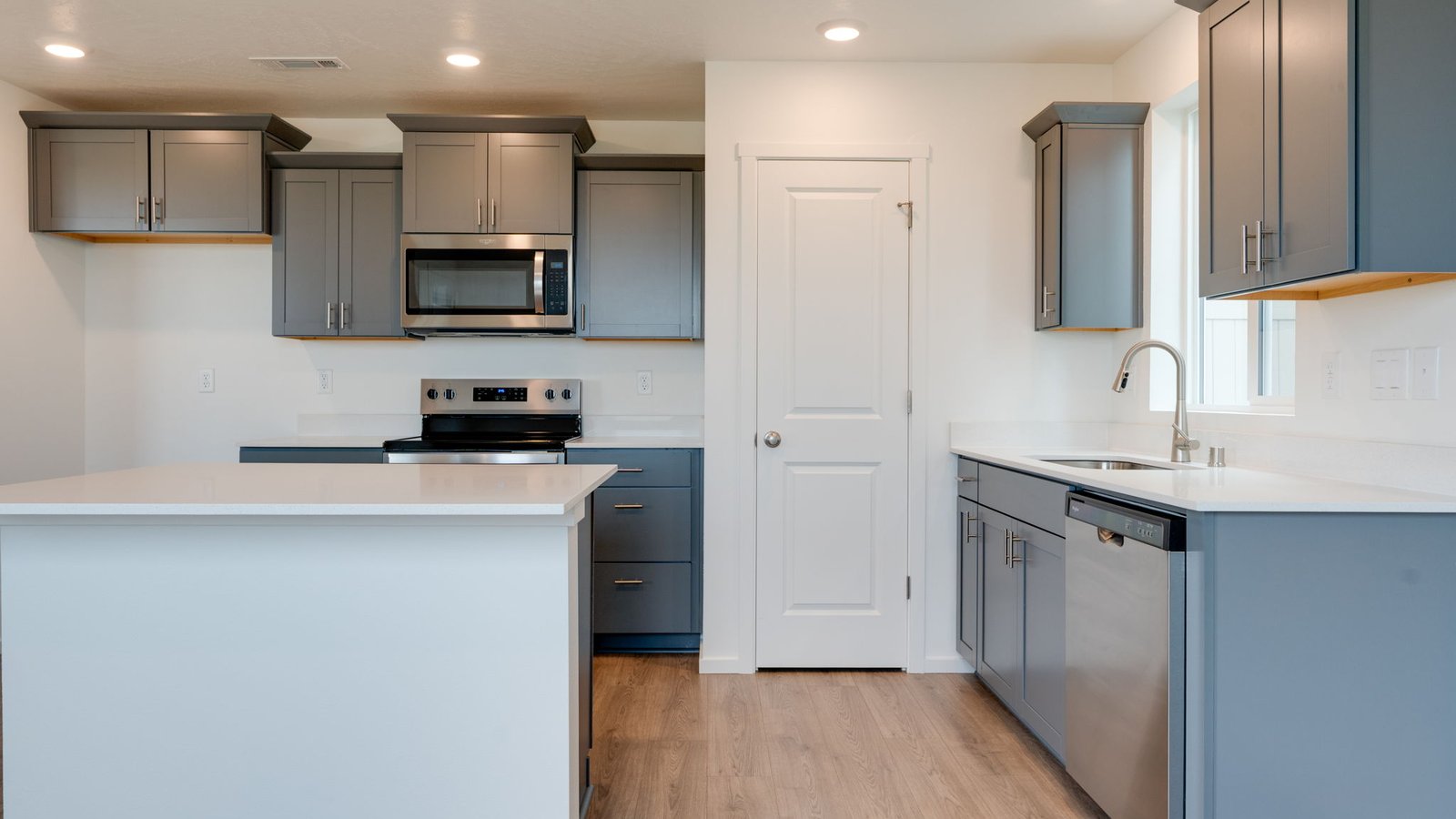 Kitchen with shaker cabinets, quartz counters, stainless steel appliances, pantry, and an island with a breakfast bar