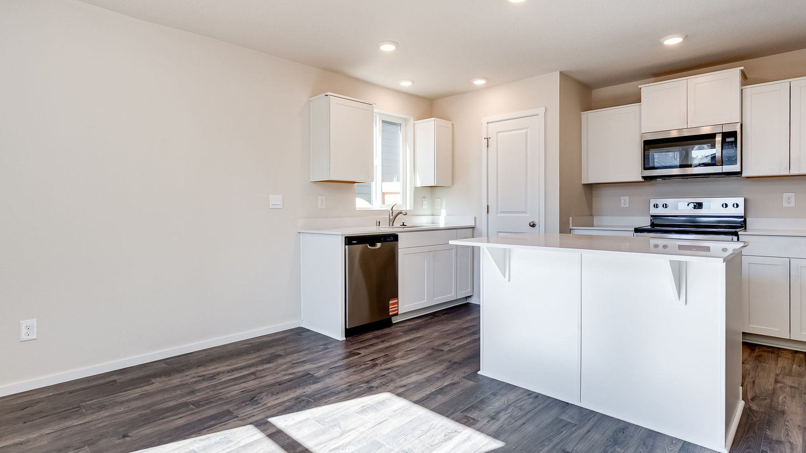 Kitchen with shaker cabinets, quartz counters, stainless steel appliances, pantry, and an island with a breakfast bar