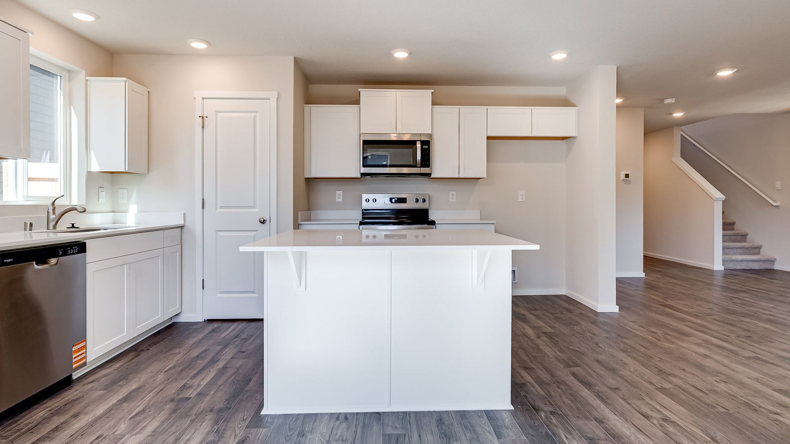 Kitchen with shaker cabinets, quartz counters, stainless steel appliances, pantry, and an island with a breakfast bar
