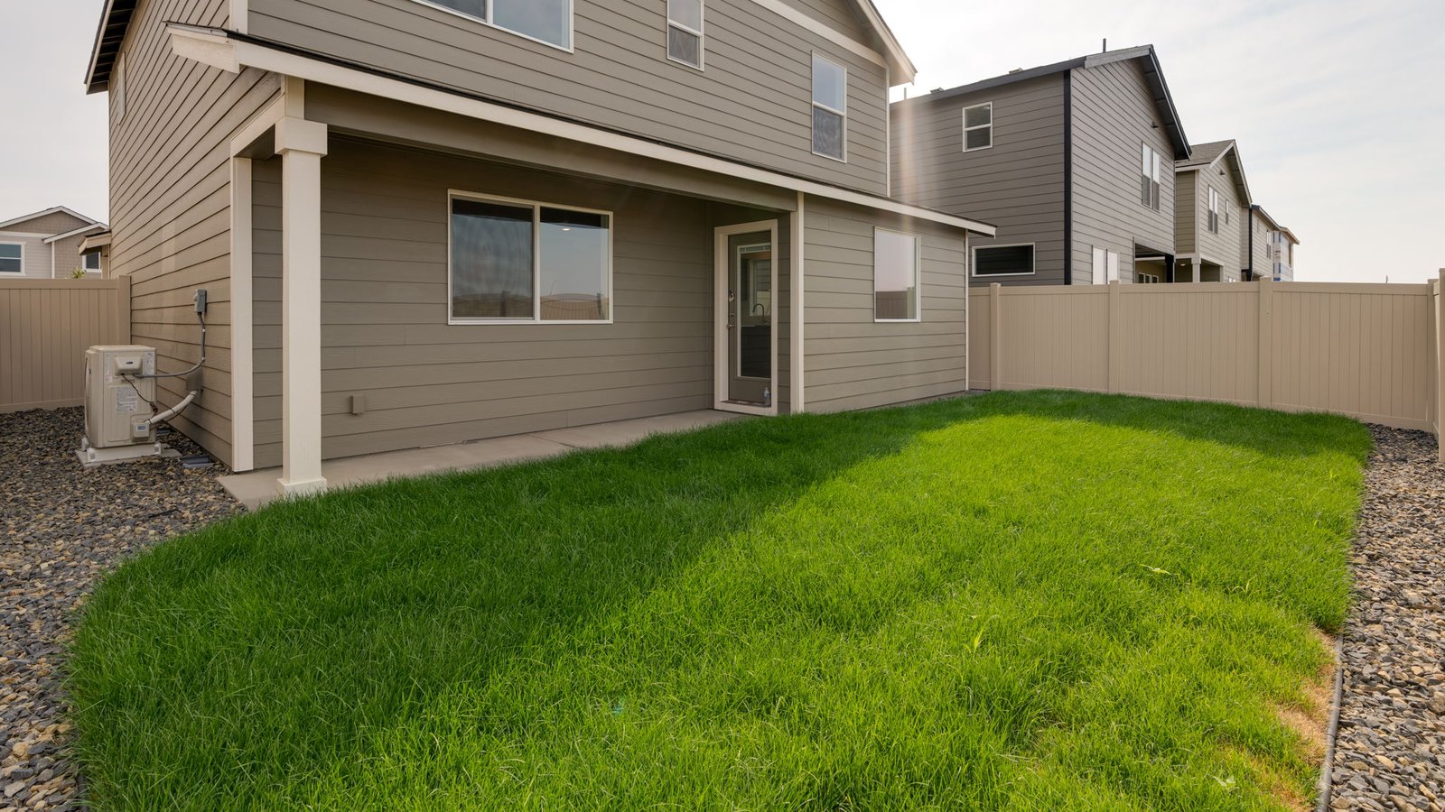fully fenced backyard with sod lawn and a patio