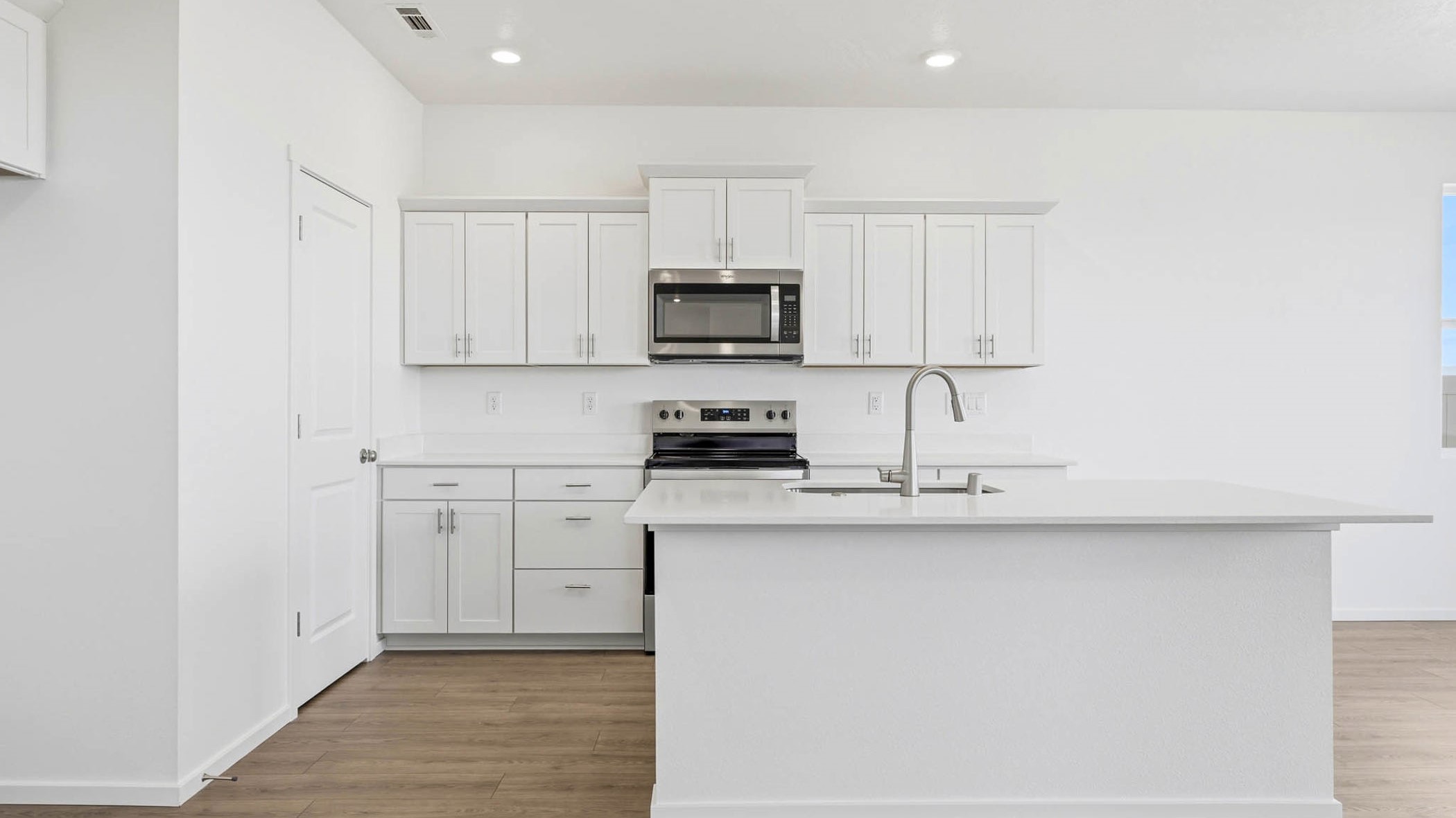 Kitchen with shaker cabinets, quartz counters, stainless steel appliances, pantry, and an island with a breakfast bar