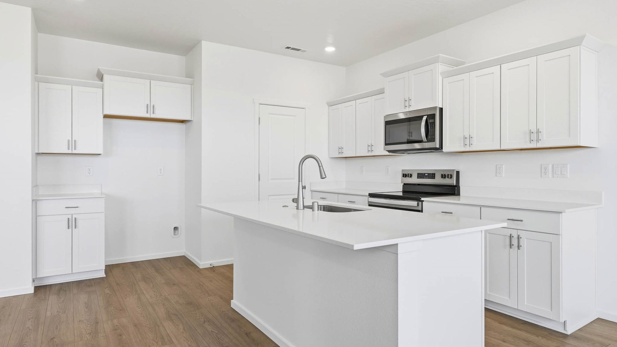 Kitchen with shaker cabinets, quartz counters, stainless steel appliances, pantry, and an island with a breakfast bar