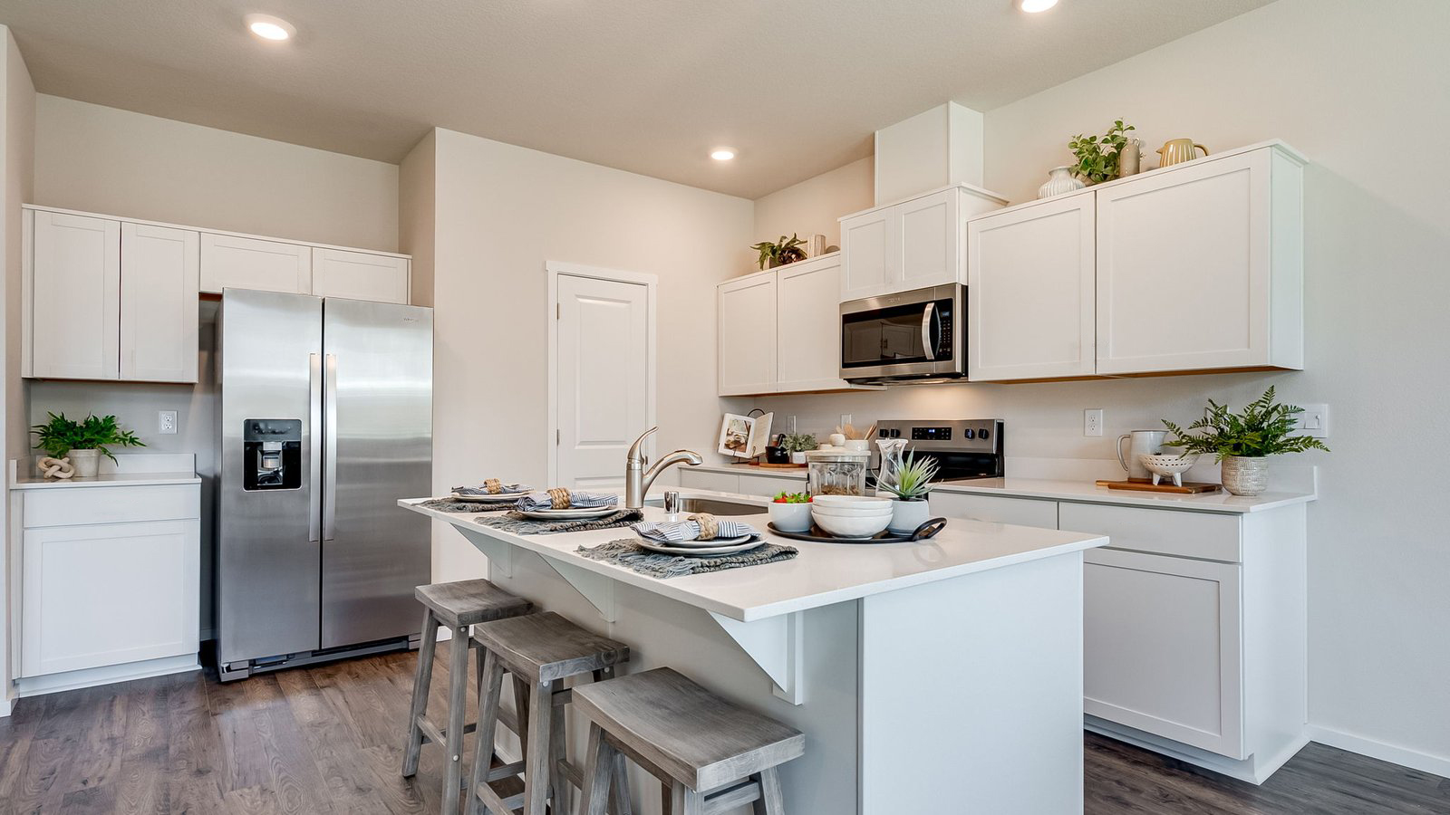 Kitchen with shaker cabinets, quartz counters, stainless steel appliances, pantry, and an island with a breakfast bar