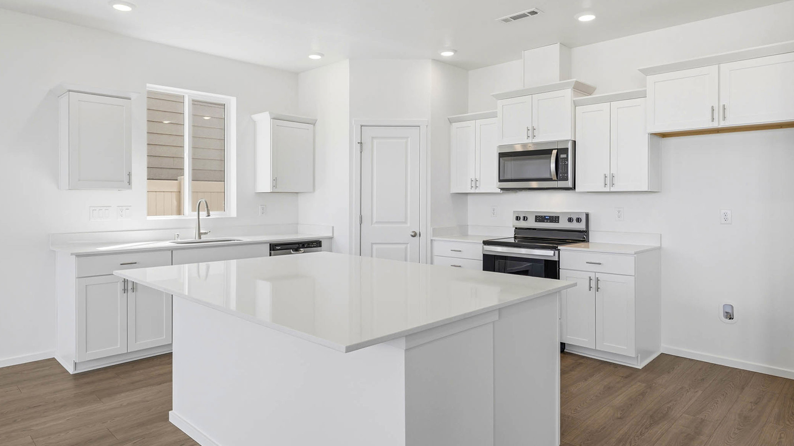 Kitchen with shaker cabinets, quartz counters, stainless steel appliances, pantry, and an island with a breakfast bar