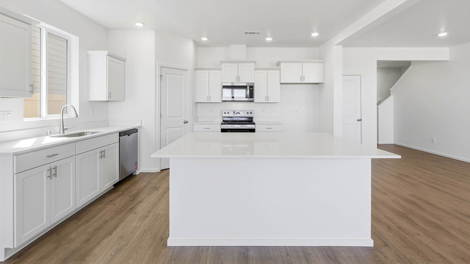 Kitchen with shaker cabinets, quartz counters, stainless steel appliances, pantry, and an island with a breakfast bar