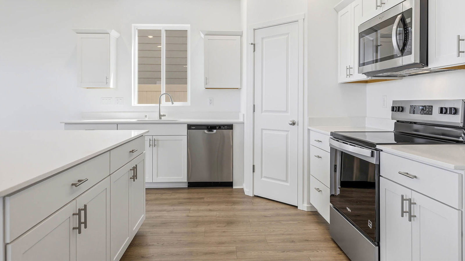 Kitchen with shaker cabinets, quartz counters, stainless steel appliances, pantry, and an island with a breakfast bar